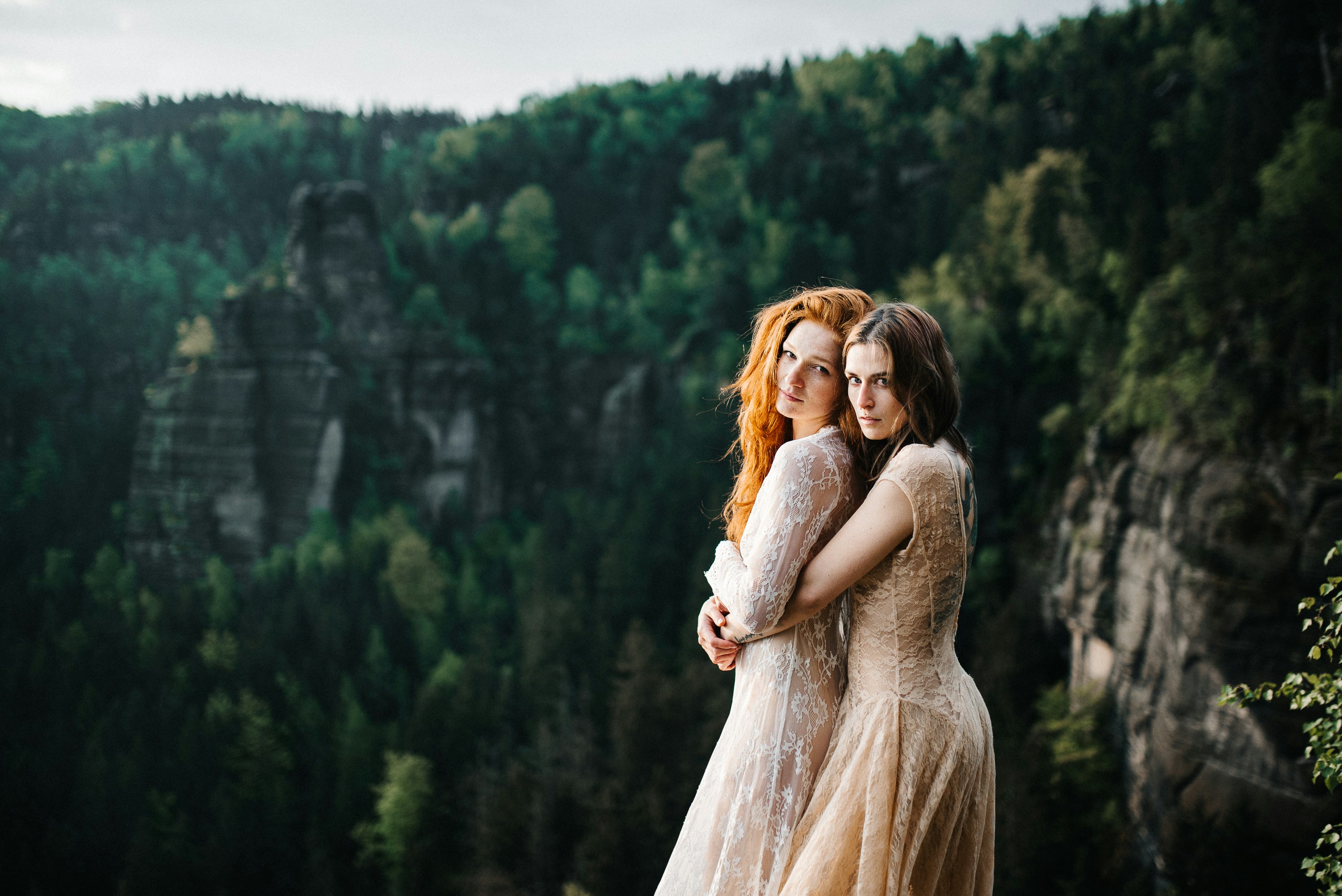 woman hugging woman at her back near trees during day